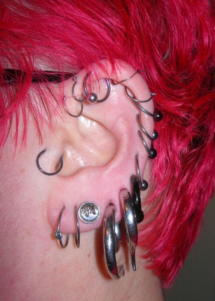 Çok sayıda küpeli bir kulak: 2 gr, 4 gr ve 6 gr piercingler, ayrıca çok sayıda sabit boncuk yüzük.