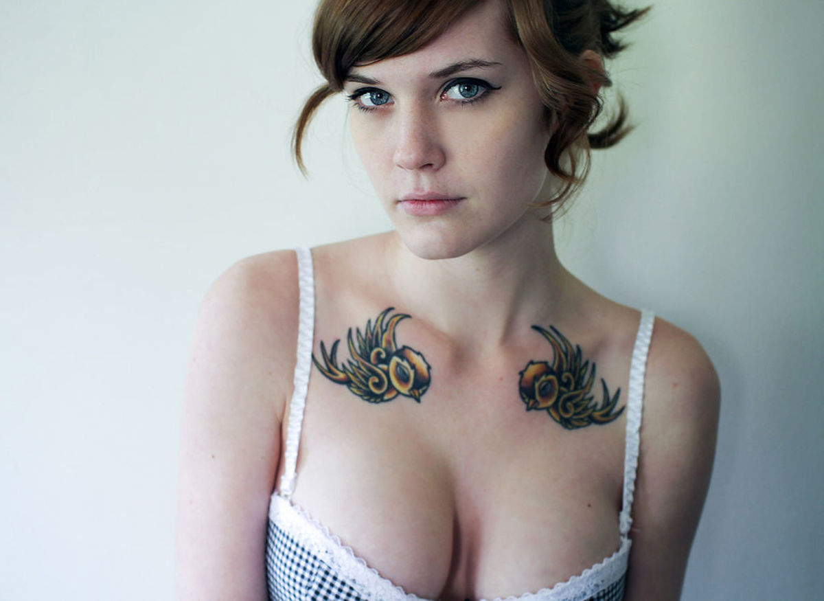 Nainen, jolla on kaksi lintu -tatuointia, yksi kummallakin puolella, solisluun yläpuolella.
